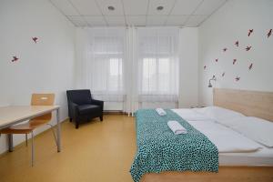 a room with a bed, chair, desk and a window at Hostel Florenc in Prague