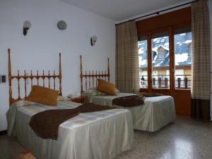 2 camas en una habitación de hotel con balcón en Hotel Garona en Bossost
