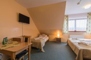 ein Hotelzimmer mit 2 Betten und einem Tisch in der Unterkunft Gościniec Pieniński in Kluszkowce