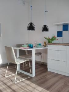a white kitchen with a white table and chairs at Apartament niebieski w kompleksie 5 Morz in Sianozety