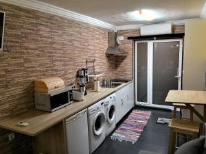 a kitchen with a washer and dryer next to a brick wall at Central Praia Beach House in Praia da Vitória