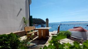 ein Picknicktisch und ein Boot auf dem Wasser in der Unterkunft Beach House Bassi in Rijeka