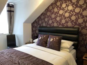 a bedroom with a large bed with a black headboard at Rosebank Guest House in Perth