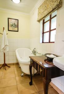 y baño con bañera y lavamanos. en Ursula's Homestead en Victoria Falls