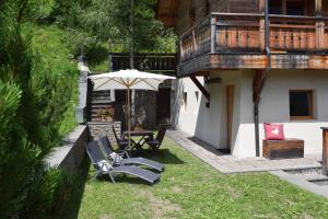a patio with chairs and an umbrella next to a house at Chalet Do Costa in Pozza di Fassa