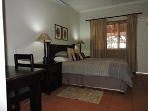 a bedroom with a bed and a desk and a window at Hluhluwe Country cottages in Hluhluwe +68 photos