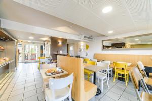 a dining room with yellow chairs and tables in a restaurant at B&B HOTEL Dijon Marsannay in Dijon