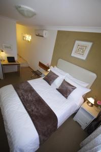 1 dormitorio con 1 cama grande con sábanas y almohadas blancas en Astoria Retreat Bed & Breakfast, en Perth