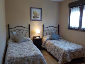 a bedroom with two beds and a lamp and a window at Las Cabraliegas in Arenas de Cabrales