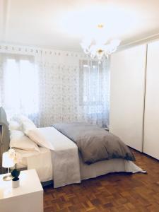 biała sypialnia z łóżkiem i żyrandolem w obiekcie Central Apartment w Wenecji