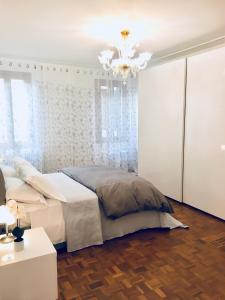 biała sypialnia z łóżkiem i żyrandolem w obiekcie Central Apartment w Wenecji