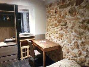 cocina con mesa de madera y pared de piedra en Le Tempo, en Entrecasteaux
