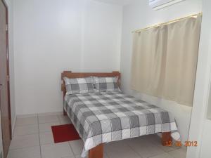 a small bedroom with a bed with a checkered blanket at Hotel Ox Inn in Uberaba