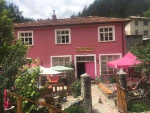 ein rosafarbenes Haus mit Tischen und Sonnenschirmen davor in der Unterkunft The Pink House in Polkownik Serafinowo