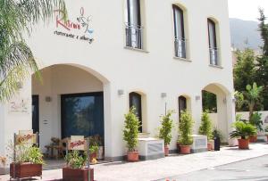 a white building with potted plants in front of it at Hotel Al Ritrovo in Castelluzzo