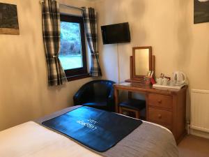 a bedroom with a bed and a desk and a window at Ben Nevis Guest House in Fort William