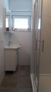 La salle de bains est pourvue d'un lavabo et d'une fenêtre. dans l'établissement Apartment Sano, à Podstrana