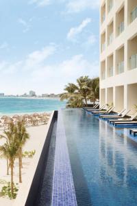 a beach with a pool, chairs, and a pool table at Turquoize at Hyatt Ziva Cancun - Adults Only - All Inclusive in Cancún