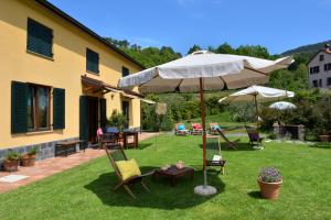 un patio con sombrilla, sillas y mesa en Il Laghello di Amina en Framura