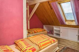 2 camas en una habitación con paredes rosas y ventana en Penzión u Maroša, en Kežmarok