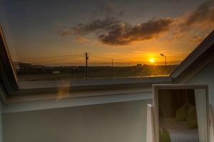 a room with a window with a bed and a sunset at The Pipers Rest in Doolin