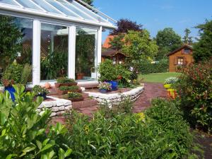 a garden with a conservatory with flowers and plants at Gaestehaus Kiekmolrin in Gnarrenburg +7 photos