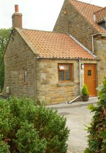 a small stone house with a brown door at The Old Dairy in Scarborough