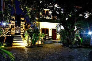 a building with a tree in front of it at night at Nakula Guest House in Kuta