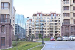 トビリシにあるAden Apartmentsの高層ビルの前に車を停めた通り