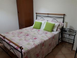 1 dormitorio con 1 cama con almohadas verdes en Casas de Santo António, en Odeceixe