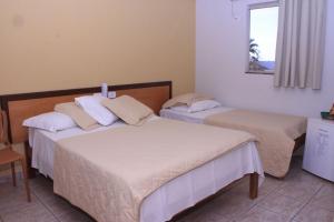 two beds in a hotel room with a window at Flip Palace Hotel in Buriti Alegre