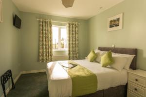 a bedroom with a bed with green walls and a window at The Pipers Rest in Doolin