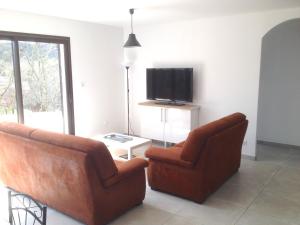 a living room with two chairs and a tv at Gîtes des Campanes in Saint Alban Auriolles