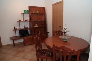 a dining room with a wooden table and a television at Casas de Santo António in Odeceixe