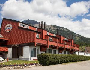 a red building with a mountain in the background at Rocky Mountain Ski Lodge in Canmore