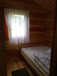 a bed in a log cabin with a window at Domki drewniane OW Latarnik in Gąski