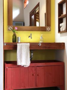 a bathroom with a red vanity with a mirror at Chalé Siriú - entre o rio e o mar in Siriú