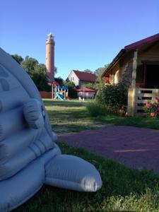 a inflatable chair in the grass with a lighthouse in the background at Domki drewniane OW Latarnik in Gąski