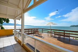 a deck with a table and chairs and an umbrella at Pousada Areia Cristal in Bombinhas