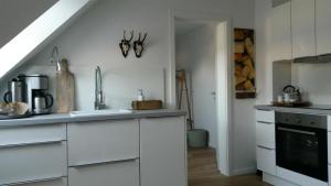 una cocina con armarios blancos y fregadero en Charmante, moderne Wohnung en Greven
