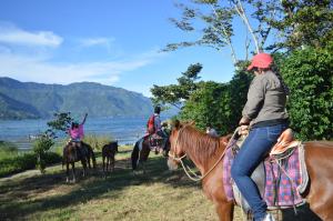 un grupo de personas montando caballos por el agua en Eco Hotel Uxlabil Atitlan, en San Juan La Laguna