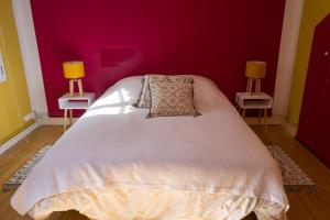 - une chambre avec un lit blanc et un mur rouge dans l'établissement Le 22, à Honfleur