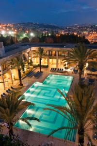 una grande piscina con palme di fronte a un edificio di Dan Jerusalem Hotel a Gerusalemme