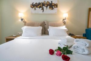 a hotel room with a bed with towels and roses at Edem Luxury Apartments in Nea Peramos