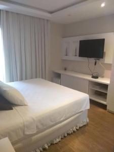 a bedroom with a white bed and a flat screen tv at Flat no Portogalo in Angra dos Reis +27 photos
