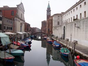 a group of boats docked in a canal with a clock tower at Hotel Touring in Sottomarina