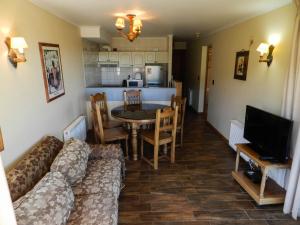 ein Wohnzimmer mit einem Sofa und einem Tisch sowie eine Küche in der Unterkunft Departamentos Amoblados Don Matias en Termas de Chillan in Nevados de Chillan