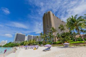 タモンにあるDusit Beach Resort Guamの建物の前のビーチ(椅子、パラソル付)