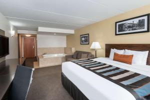 um quarto de hotel com uma cama grande e uma banheira em Wingate by Wyndham Bowling Green em Bowling Green