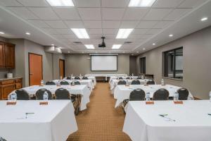 una sala de conferencias con mesas y sillas blancas y una pantalla en Wingate by Wyndham Bowling Green en Bowling Green